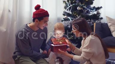 家中圣诞树附近有圣诞礼物的家庭和宝宝。 儿童打开礼品盒。